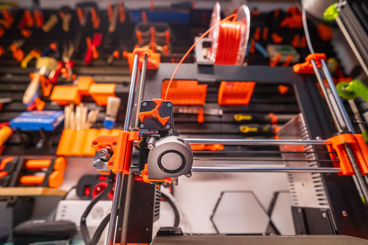 Imprimante 3D à dépôt de filament dans un atelier, outils rangés au mur